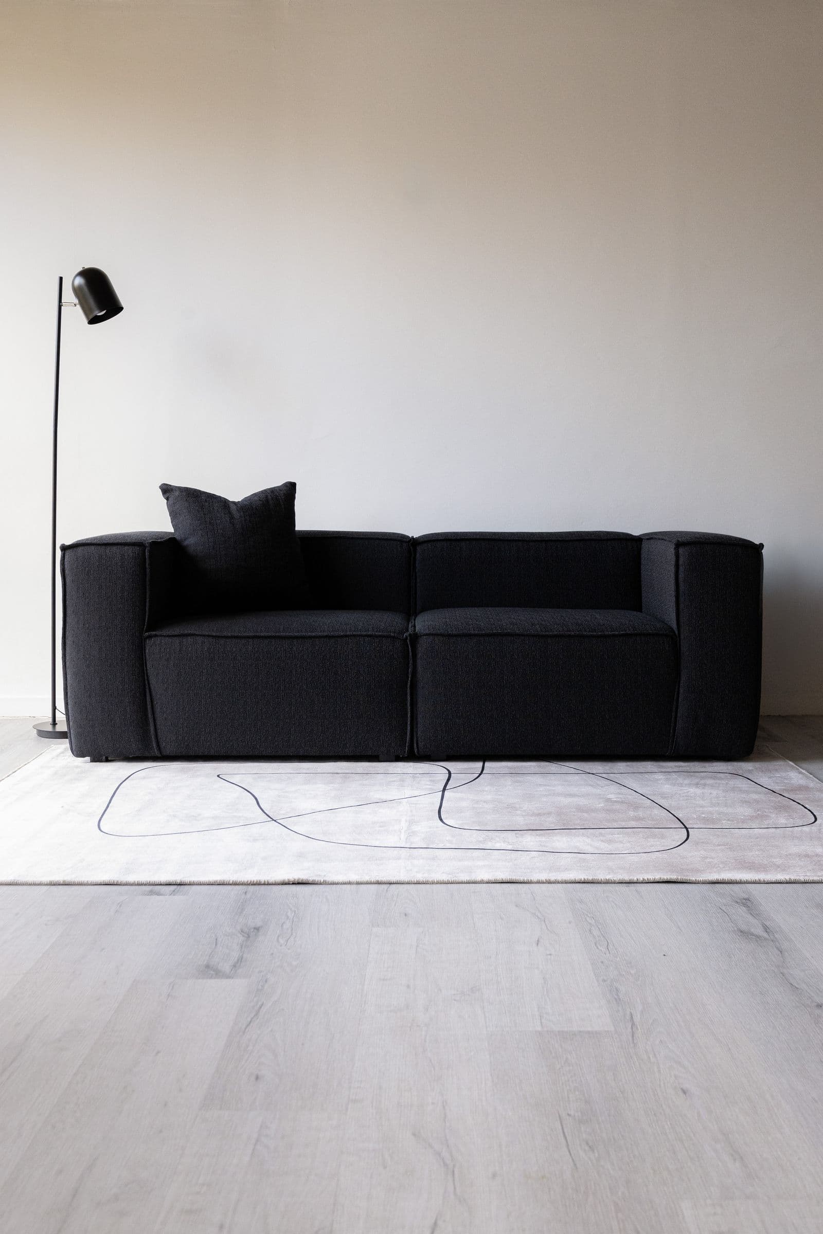 Cuarzo — Sofá modular en bouclé negro de textura gruesa, esquinas redondeadas.
